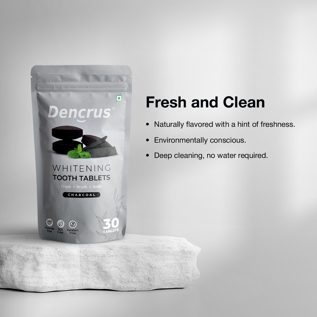 A package of Dencrus whitening tooth tablets with charcoal flavor displayed on a white stone with a white background