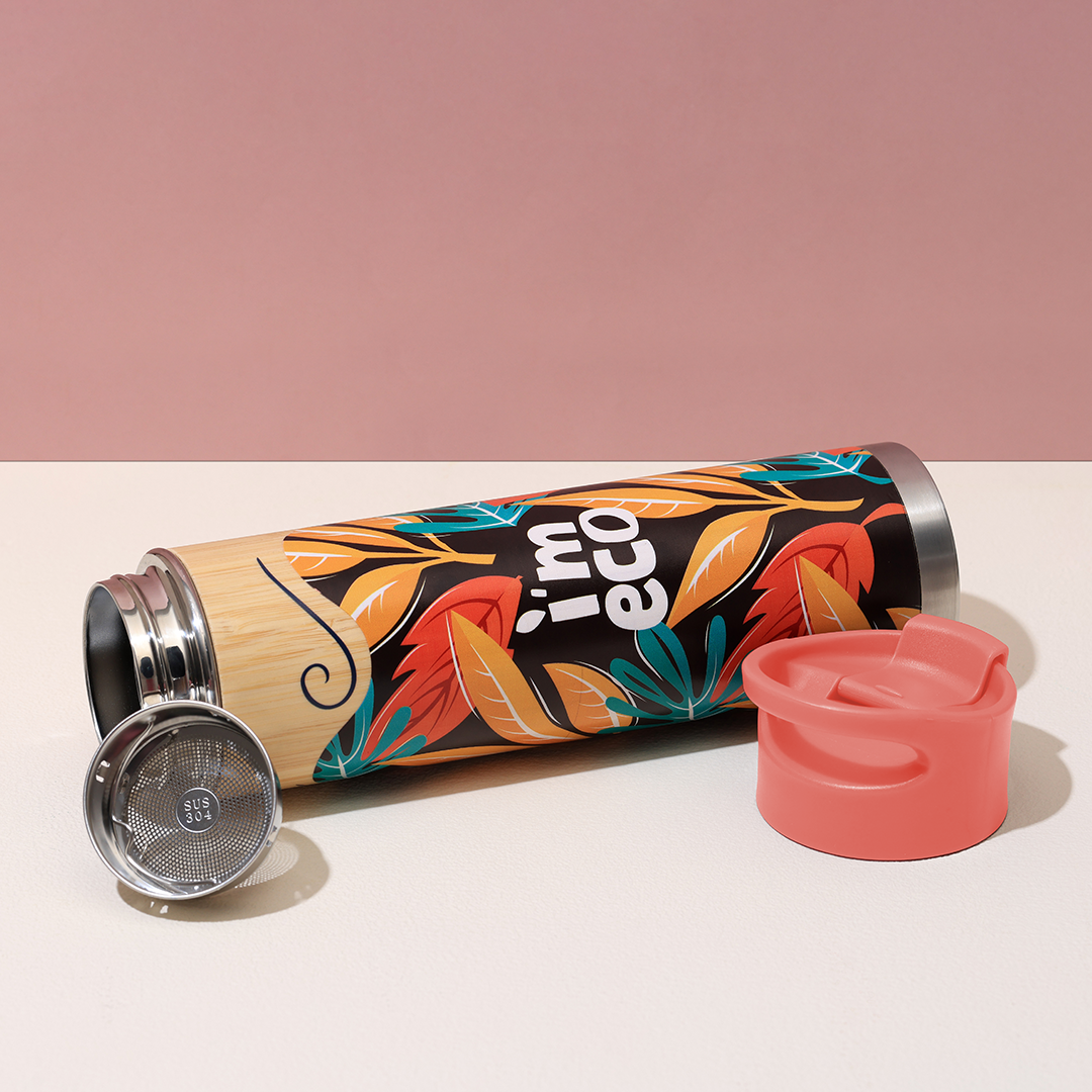 A red bamboo water bottle is opened and placed on a white table.