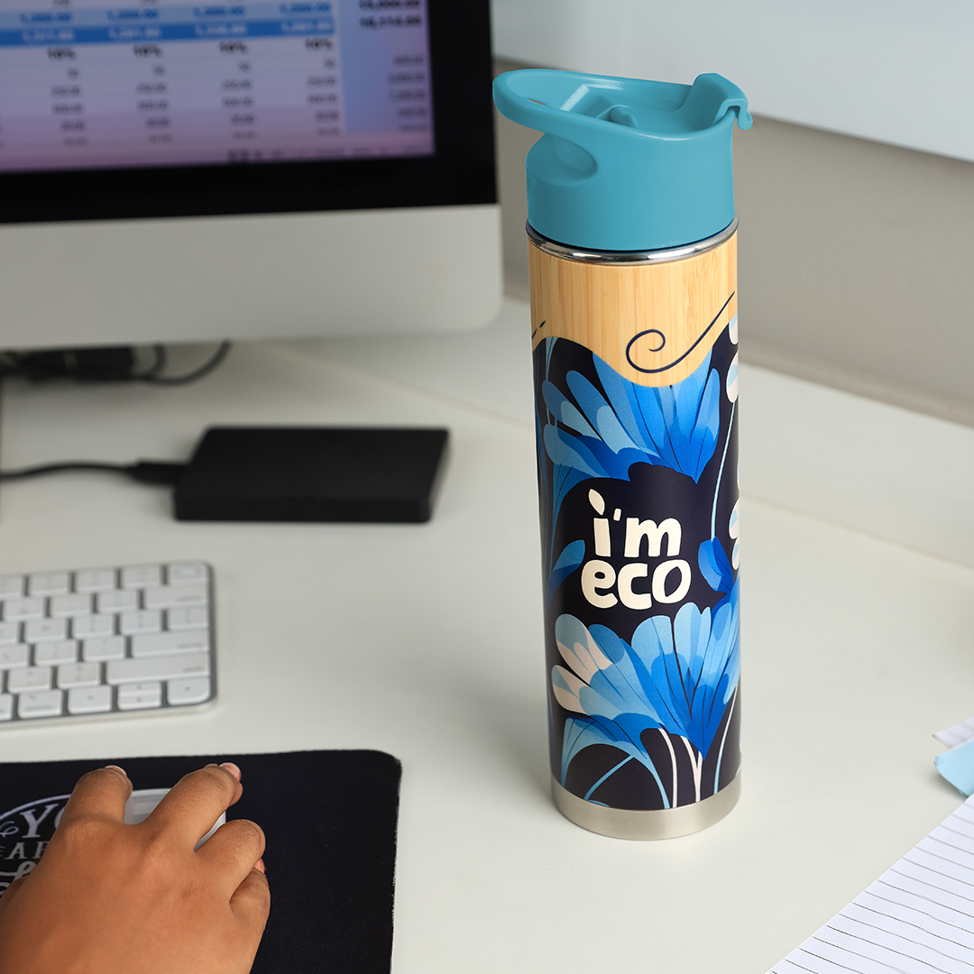 IMECO blue bamboo printed water bottle placed on office desk while a person is working on desktop.