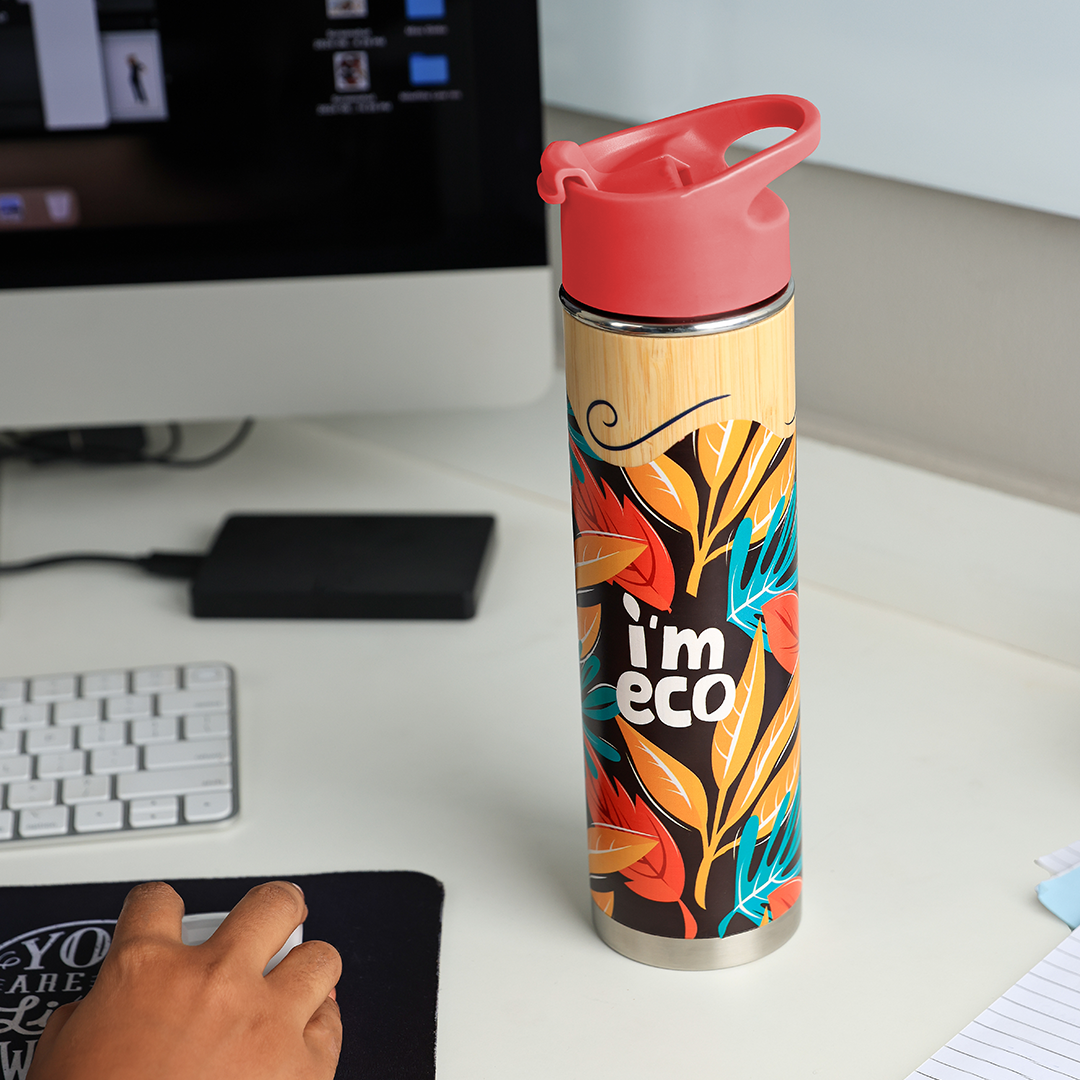 IMECO red bamboo printed water bottle placed on office desk while a person is working on desktop.