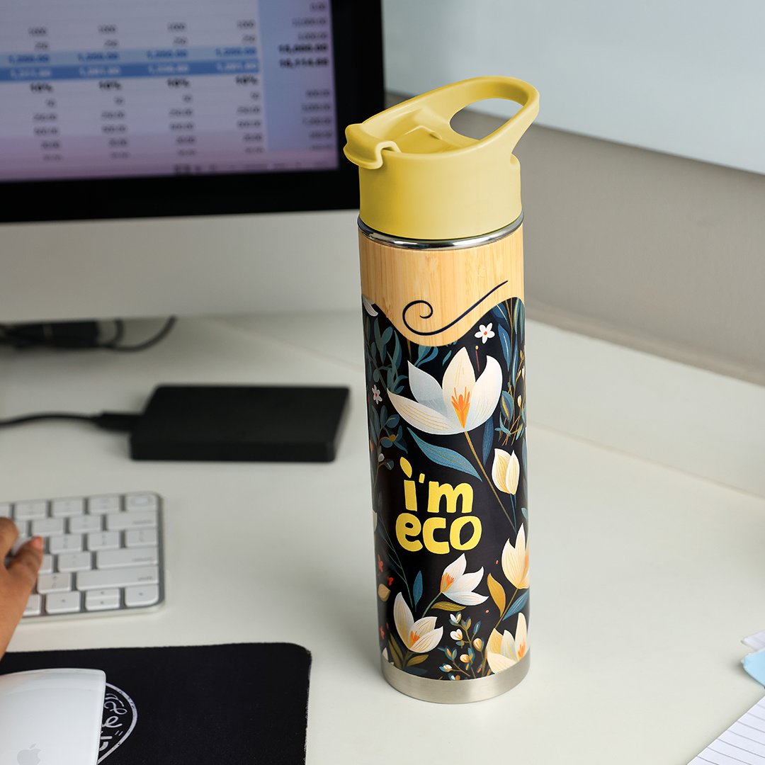 IMECO yellow bamboo printed water bottle placed on office desk while a person is working on desktop.