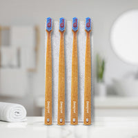4 bamboo toothbrushes with blue and red bristles, standing upright. They are placed on a bathroom counter.