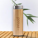 IMECO Bamboo Flat lid Bottle with stainless steel lid is placed on wooden surface against a white background