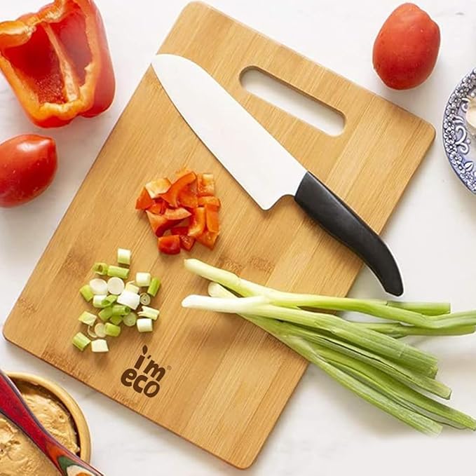 IMECO Bamboo chopping board with a kitchen knife on top, surrounded by diced vegetables and a whole tomato, with the text 'imeco' visible on the board.