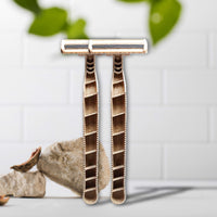 Two Shaveco bamboo husk razors are placed on a light surface with green leaves in the background