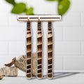 Set of three Shaveco bamboo husk razors on a white background with green leaves in the corner.