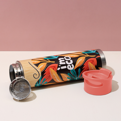 A red bamboo water bottle is opened and placed on a white table.