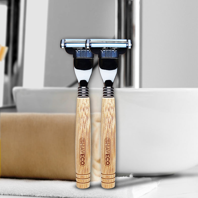 2 bamboo razors are placed together beside a towel. 