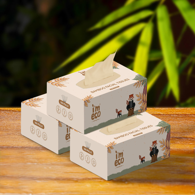 Three boxes of IMECO bamboo facial tissues on a wooden surface with a blurred green background.