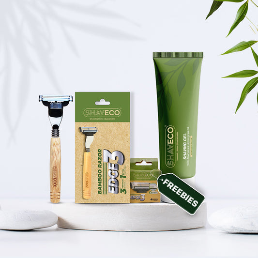 Shaving products, including a razor, extra cartridges, and shaving gel, on a white background with green leaves.