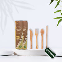 Bamboo products, including packages of reusable bamboo towels and a cutlery set, on a white surface with leaves in the corner