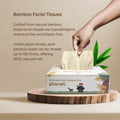 box of bamboo facial tissues with a hand reaching for a sheet, set against a beige background.
