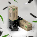 Two packs of Dencrus Bamboo Charcoal Toothpaste presented against a white background with leaves and blurry charcoal particles 