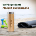 IMECO Bamboo Flat lid water bottle with 'imeco' branding on a wooden surface with fitness equipment in the background.