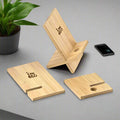 Two IMECO Bamboo Mobile Stands are there. One is assembled and one disassembled, placed on a white surface there is a phone and flower pot