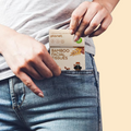 A man is pulling a pack of IMECO Pocket Tissues from his jeans pocket against a light background