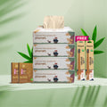 packaging of eco-friendly products including tissues, toothbrush and ear swabs on a green background with leaves.