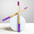 Two ORBY Plus lavender-coloured bristles bamboo toothbrush placed on a round white block against a white background 